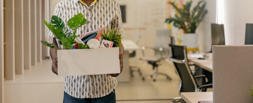 Homme portant un carton avec des affaires de bureau