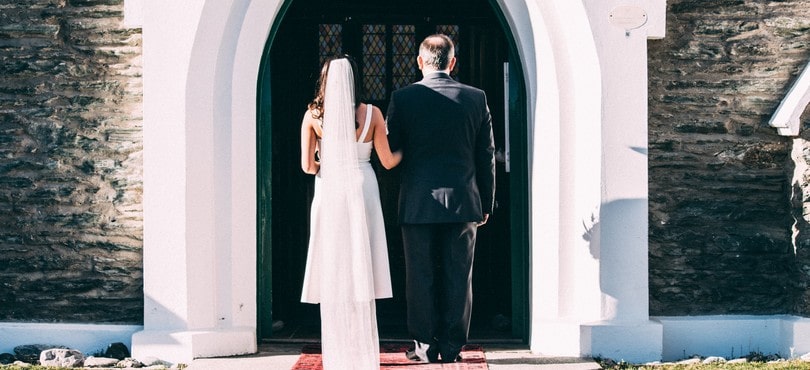 Comment organiser son mariage à l'église ? Mariée au bras de son père devant l'église