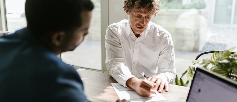 Homme signant un contrat de travail avec une clause d'exclusivité